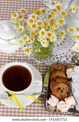 Table setting with chamomiles on checkered tablecloth