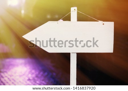 Wooden white pointer with an arrow to the party. Bright purple lights.