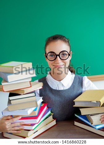 Smiling student hugs books. Photo of girl in uniform, wearing glasses. Education concept