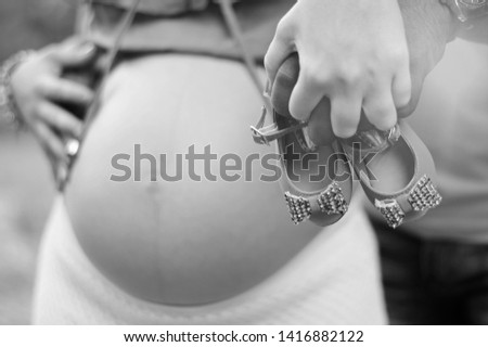 Mother and father holding baby's shoe in foreground with blurred background