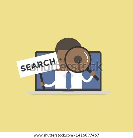 African businessman holding SEARCH sign and looking through a magnifying glass in computer notebook.