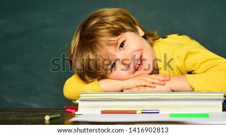 Back to school and happy time. Kid is learning in class on background of blackboard. Cheerful smiling child at the blackboard.