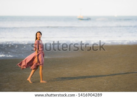 Portrait young beautiful asian woman walk smile and happy on the beach sea and ocean for leisure travel in holiday vacation