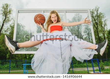 A full length portrait of a sporty teenager girl posing on the basketball pinch in a white fluffy skirt. Sport fashion, active lifestyle, basketball.