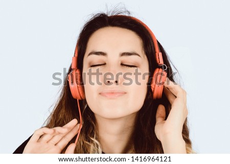 Beautiful young girl listening to music with red headphones in studio.