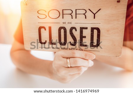 Hand holding closed sign woodboard in hand