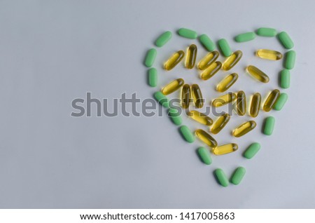 Mixed pills are laid out in the form of a heart and lie on a white background. Horizontal view