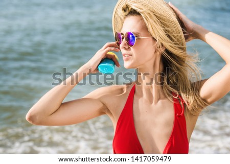 attractive woman holds sunblock cream on the beach