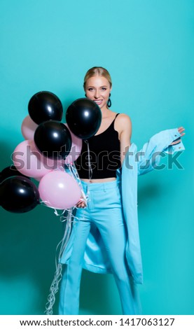 Beautiful girl with bunch colorful air balloons laughing over Blue background. Birthday Holiday party. Beautiful Happy Young woman having fun, playing and celebrating with color balloon- Image     