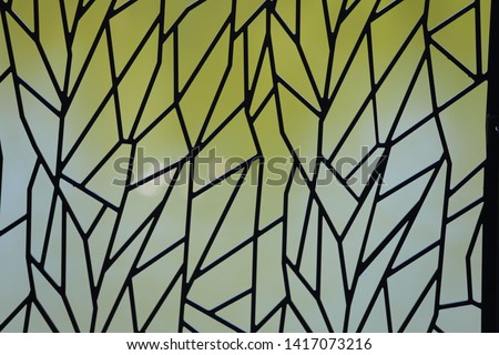 Abstract picture of a window made of polygonal pieces of glass. Artistic design with many black lines and a blur green grey background. Decorative element.