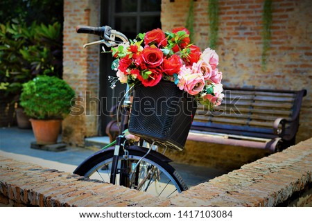 Picture of bicycle carrying bouquet of roses standing in the middle of corner in the outdoor summer garden