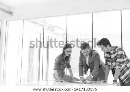 Black and White photo of Creative business people discussing over photographs in office