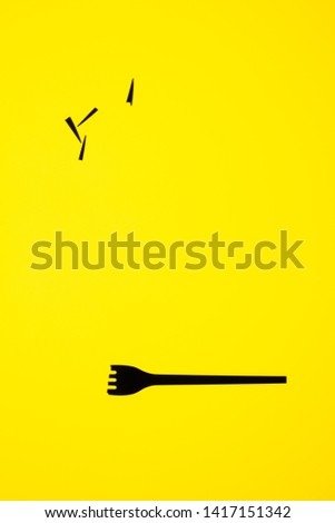 View of black fork on yellow background. The fork has its teeth broken and separated from the main body