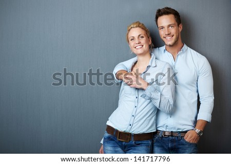 Portrait of a young couple standing against blue gray background