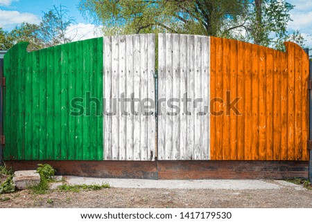 Close-up of the national flag of Ireland on a wooden gate at the entrance to the closed territory on a summer day. The concept of storage of goods, entry to a closed area, tourism in Ireland