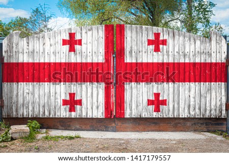 Close-up of the national flag of Georgia on a wooden gate at the entrance to the closed territory on a summer day. The concept of storage of goods, entry to a closed area, tourism in Georgia