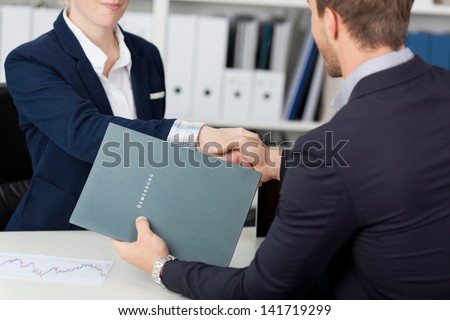 Midsection of a businessman shaking hands with a female interviewer in office Royalty-Free Stock Photo #141719299