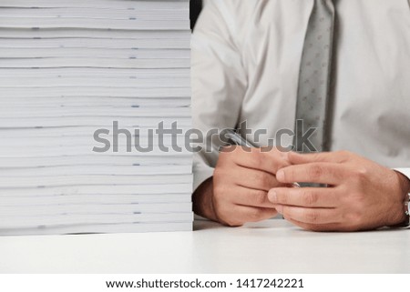 Businessman working at an office, reads stack of books and reports. Business financial accounting concept.