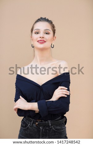 Smiling fashion model wearing navy blue blouse on beige background