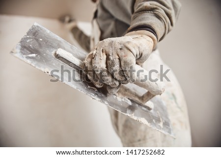 Workman plastering gypsum walls inside the house. Royalty-Free Stock Photo #1417252682
