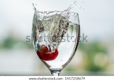 strawberry falls into a glass of water