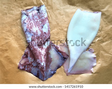 Two wet fresh raw squid treated and untreated are on yellow paper for baking