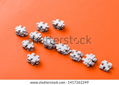 top view of direction arrow with jigsaw puzzle pieces on orange