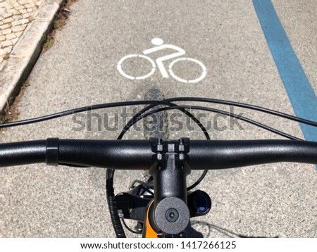 Handlebars of a bike see from above on a cycle lane with the logo on the road