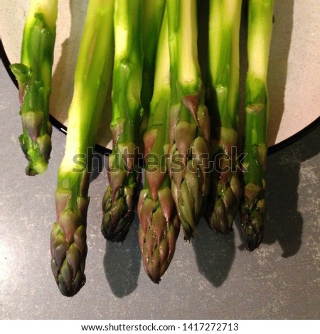 Macro Photo food boiled green asparagus. Texture background peeled asparagus stalks under lemon juice. Image of vegetable cooked asparagus on a plate