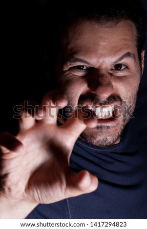 Aggressive man attacks with his hand in a scary night scene.