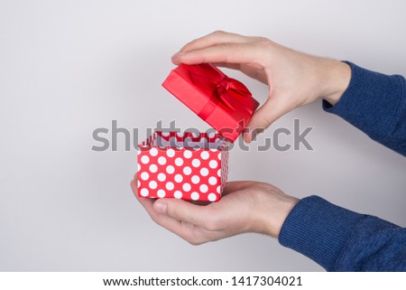 Close-up studio photo shot of student's palms touching little case cap cover of red cute beautiful package blue pullover jumper sweater isolated grey background