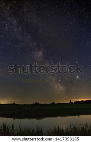 Bright stars of the Milky Way galaxy over the river in the night sky. Outer space photographed with long exposure.