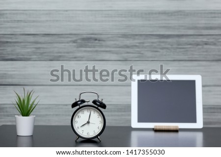 Clock with alarm clock and home plant in a pot Tablet computert, notebook, phone on the table. The mode of the day, schedule, free and work time.