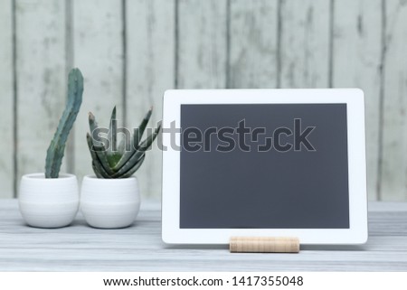 Tablet computer, home plant, notebook, phone on the table. Work at home. Gadgets and electronics.