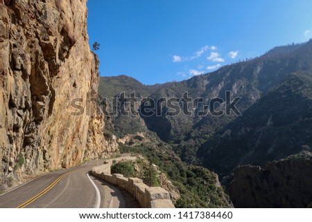 Landscape of road along sheer cliff with mountains in the background at Kings Canyon National Park in California                              