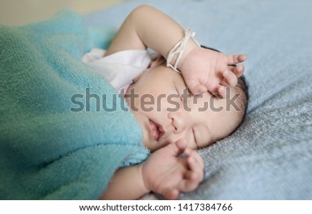  Asian little baby  sleeping on a blue blanket in bedroom . Asian Infant nappy change after bath or shower. close up Happy adorable asian baby on the bed
