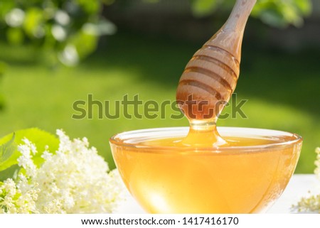 honey spoon over a transparent bowl of honey