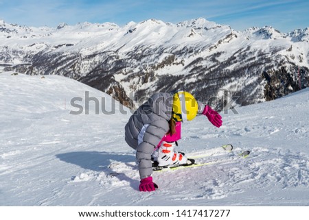 Little girl learning to ski on the ski slopes in the high mountains