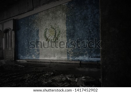painted flag of guatemala on the dirty old wall in an abandoned ruined house. concept