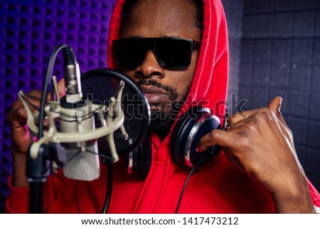 afro american man headphones in a cap and a hood sunglasses recording hip hop song track.