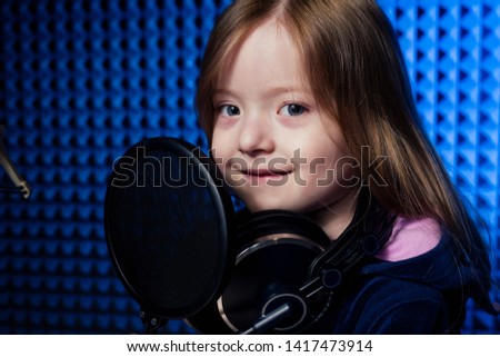 girl star singer artist in a black blouse with headphone recording new song with microphone.