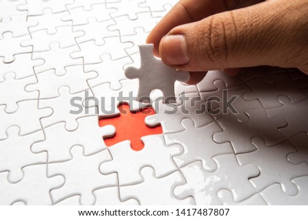hand holding piece of blank jigsaw puzzle for copy space, replacement words or text. Close up selective focus.