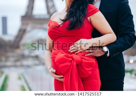 Pregnancy photo of a couple in Paris in front of the Eiffel tower with a bow on the belly