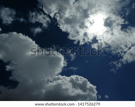 Sun behind white cloud on blue sky.