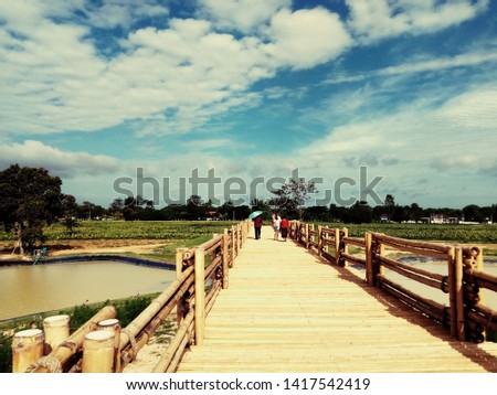 Granddaughter and Grandma to see the bamboo bridge and watch the sunflower fields. There is a bright blue background.