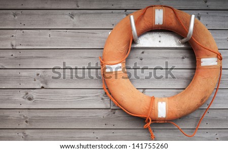 Red lifebuoy with rope on weathered wooden wall in port Royalty-Free Stock Photo #141755260