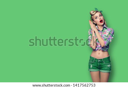 Excited surprised beauty woman. Girl in pin up fashion style. Blond model at retro and vintage concept. Green color background. Copy space for some advertise slogan, imaginary or text. 