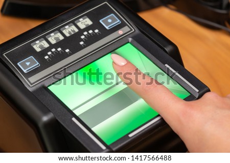 The process of scanning fingerprints during the check at border crossing. Female hand puts fingers to the fingerprint scanner. Biometric, identity verification and border control, immigration concept Royalty-Free Stock Photo #1417566488