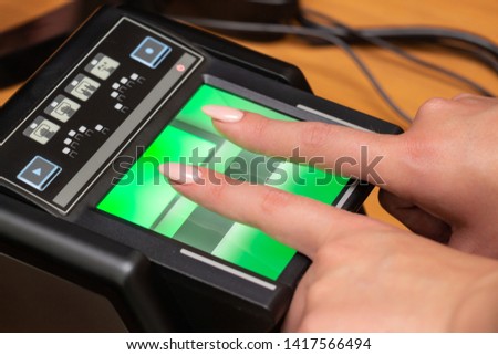 The process of scanning fingerprints during the check at border crossing. Female hand puts fingers to the fingerprint scanner. Biometric, identity verification and border control, immigration concept Royalty-Free Stock Photo #1417566494