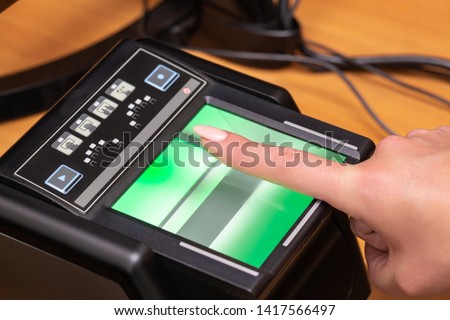 The process of scanning fingerprints during the check at border crossing. Female hand puts fingers to the fingerprint scanner. Biometric, identity verification and border control, immigration concept Royalty-Free Stock Photo #1417566497